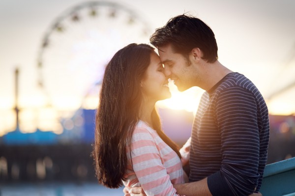 romantic couple in front of santa monica amusement park at sunse